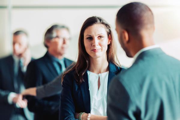 woman and man standing in a room with others conversing 