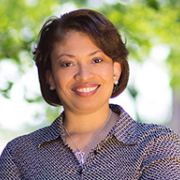 woman with short hair smiling, standing in front of trees