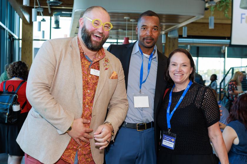 three people standing with arms around each other smiling 